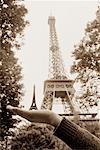 Hand Holding Model of Eiffel Tower in Front of Eiffel Tower, Paris, France