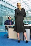 Businesswoman Standing at Businessman's Desk