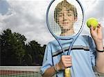Boy holding tennis racket and ball