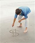 Man Drawing Dollar Sign on the Sand
