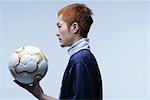 Side view of soccer player holding ball