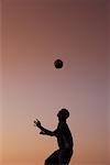 Silhouette de jongler avec le ballon sur la tête de l'homme