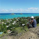 Homme avec des jumelles, assis sur une colline, Hawaii