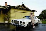 Woman Leaning Against Car In Driveway