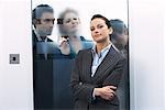 Business People Peering at Businesswoman through Glass