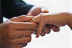 Groom placing wedding ring on brides finger