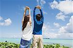 Couple with arms raised by ocean