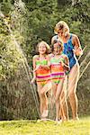 Mother and Daughters Playing with Sprinkler