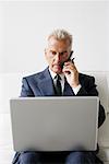 Businessman Using Cellular Phone and Laptop