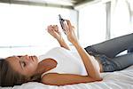 Woman Lying on Bed, Using Electronic Organizer
