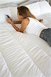 Femme allongée sur le lit, à l'aide de téléphone portable