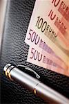 Various Euro bank notes with pen on top of wallet, close-up