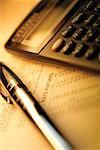 Calculator and pen on top of list of financial data, close-up
