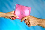 Close-up of a man and a woman's hands holding a compact disk