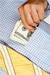 Mid section view of a businessman putting money into his shirt pocket
