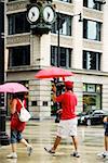 Profil de côté des piétons marchant avec parasols sur un trottoir, Chicago, Illinois, USA