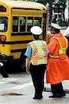 Rear view of two crossing guards standing beside a school bus, Chicago, Illinois, USA