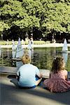 Vue arrière d'un garçon et une fille assise à côté d'une lac, état de New York City, New York, USA