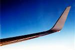 Close-up of an airplane wing against blue sky