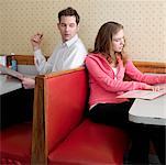 Young Woman Reading Menu in Diner with Man Looking Over Shoulder