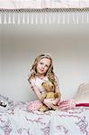 Girl Sitting on Bed, Holding Teddy Bear and Wearing Tiara