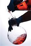 Close-up of a person pouring chemicals into a beaker