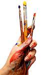 Close-up of a person's hand holding paintbrushes