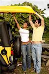 Young woman and a mid adult man loading a kayak on a jeep