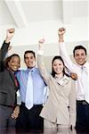 Portrait of two businessmen and two businesswomen standing with their hands raised