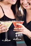 Two young women toasting martinis