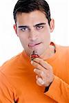 Portrait of a mid adult man holding a chocolate dipped strawberry in front of his mouth