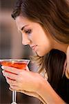 Side profile of a young woman holding a glass of martini