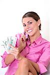 Portrait of a young woman talking on a mobile phone and holding US paper currency