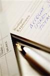 Close-up of a pen with a bank deposit slip and a personal organizer