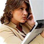 Close-up of a businesswoman holding a laptop while talking on a mobile phone