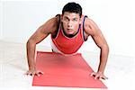 Portrait of a young man doing push-ups on an exercise mat