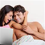 Young couple using a laptop on a bed