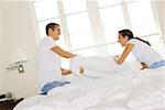 Side profile of a young couple having a pillow fight