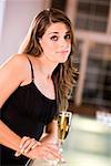 Portrait of a young woman standing at the bar counter holding a champagne flute