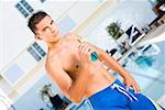 Portrait of a young man holding a cocktail at the poolside