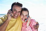 Couple Using Cell Phones At Beach