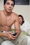 Couple on Bed, Man Holding Remote Control