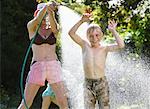 Mother Spraying Son With Hose