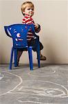 Boy Sitting in Chair, Looking Angry