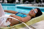 Side profile of a young woman relaxing on a lounge chair