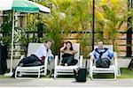 Two businessmen and a businesswoman sitting on lounge chairs