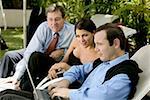 Two businessmen and a businesswoman working on a laptop