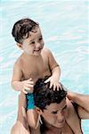 Nahaufnahme eines Vaters mit seinem Sohn auf seinen Schultern in einem Schwimmbad