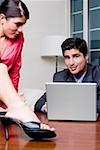 Businessman sitting in front of a laptop with a businesswoman looking at him