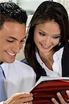 Close-up of a businessman and a businesswoman reading a book